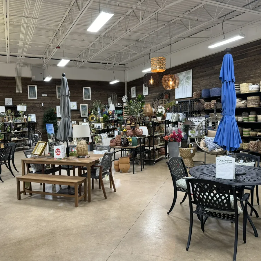 Indoor store showcasing outdoor furniture, umbrellas, woven baskets, lamps, and garden decor on display.