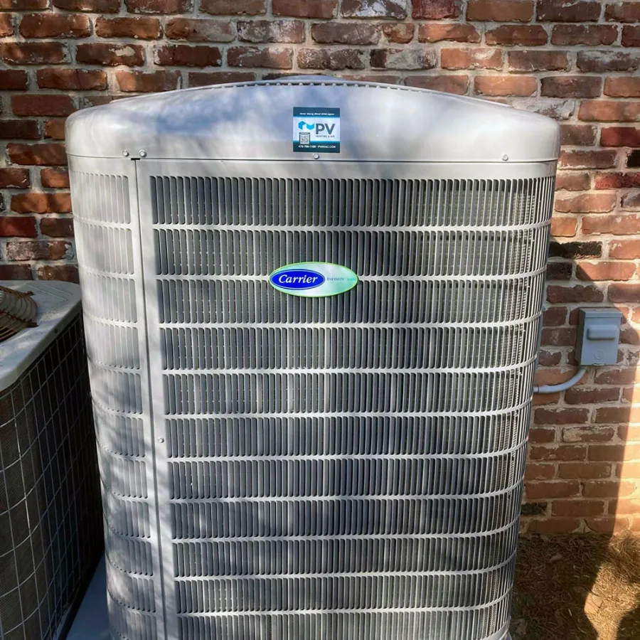 Carrier air conditioning unit against a brick wall, showcasing modern HVAC technology in residential setting.