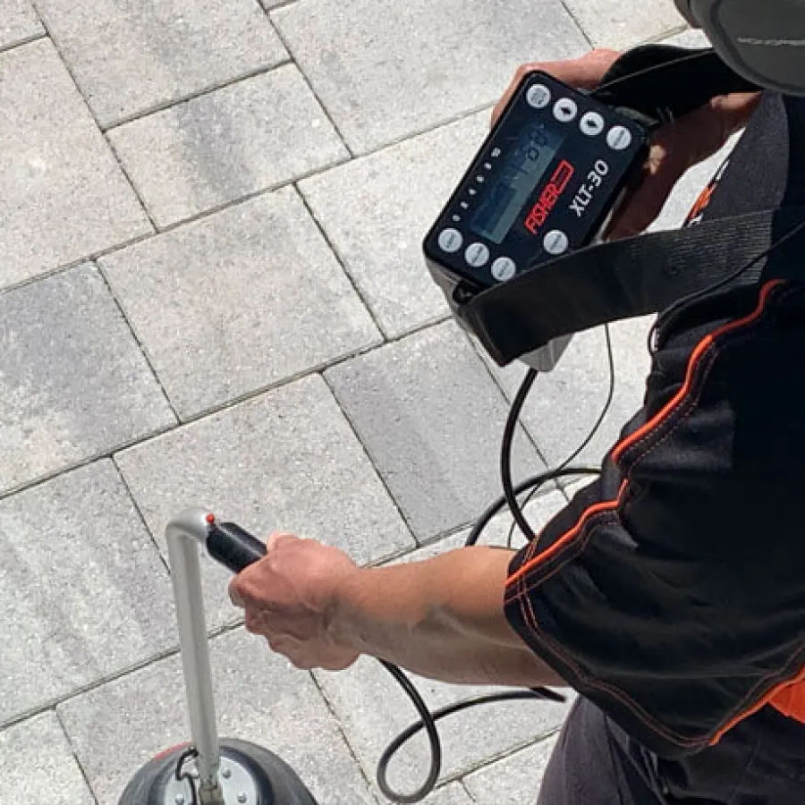 An operator using a ground penetrating radar device on a paved surface.