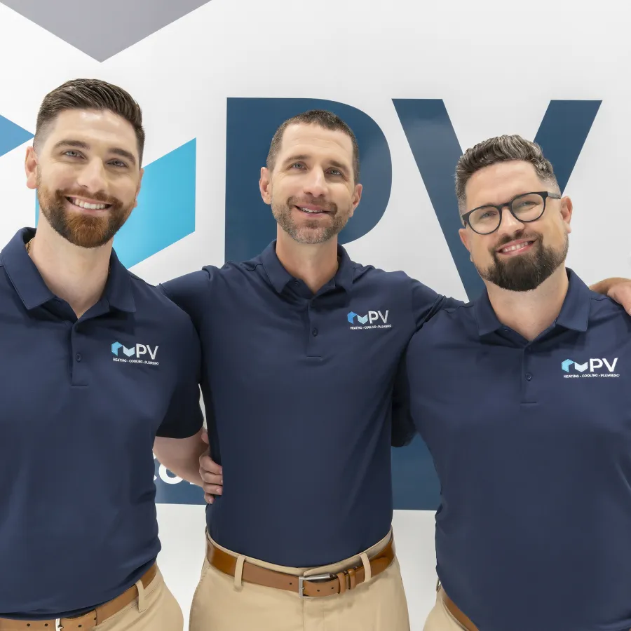 Three men in navy blue PV polo shirts posing and smiling in front of a PV branded background