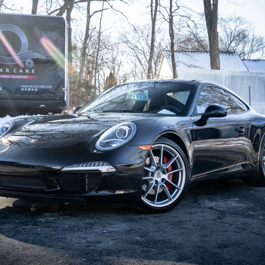 a black sports car parked on a road with snow and trees