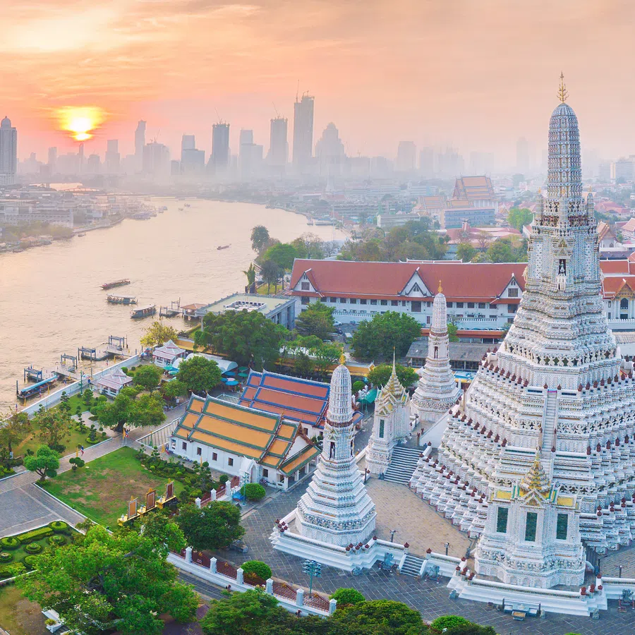 Sunset over Bangkok river with Wat Arun temple and city skyline in soft evening light