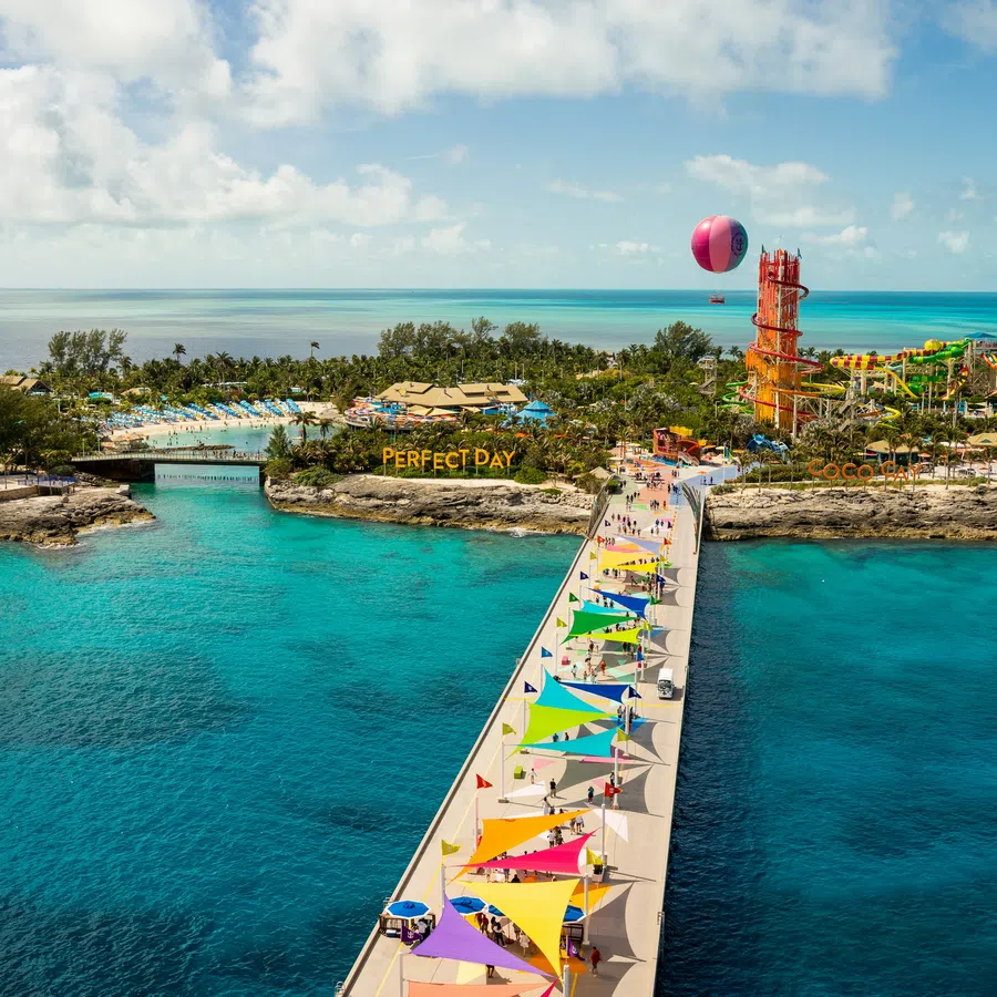 Aerial view of colorful pier leading to a tropical island water park with clear blue ocean and sky.
