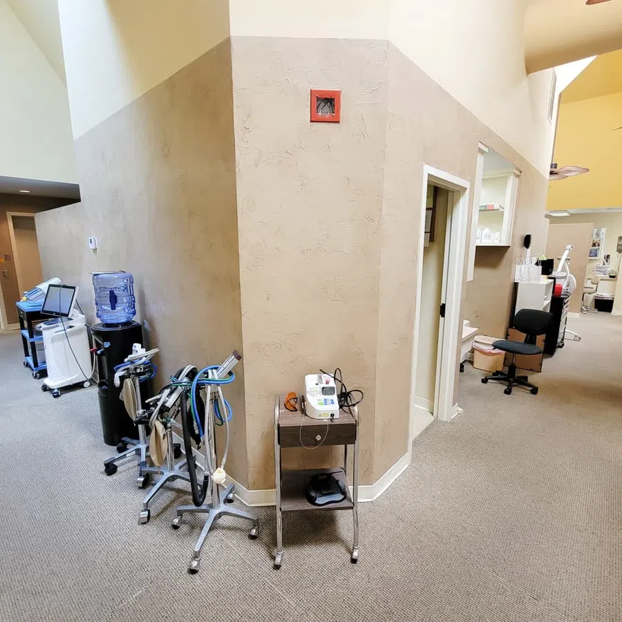 Interior hallway of a medical or dental clinic with equipment carts and treatment rooms on either side.
