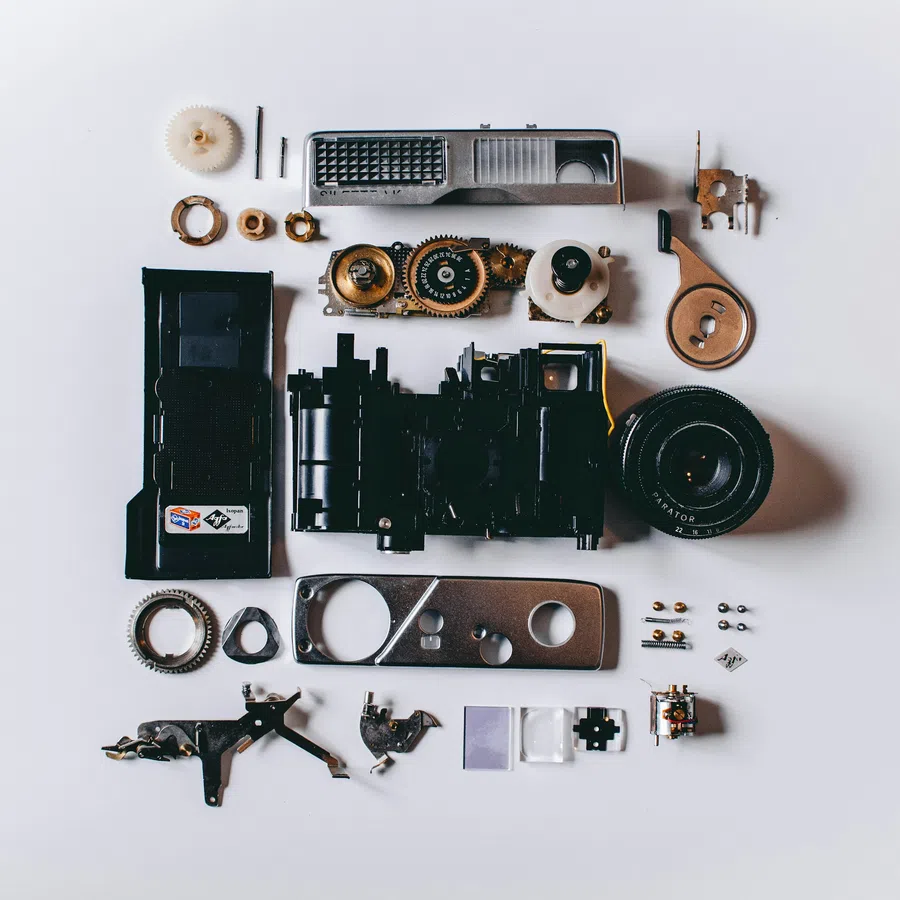 Disassembled vintage camera parts neatly arranged on a white background viewed from above