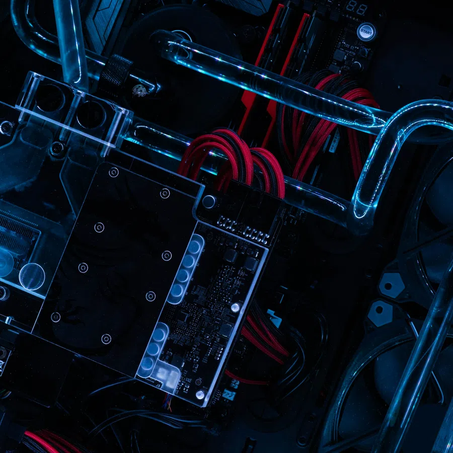 Close-up of a custom water-cooled PC with illuminated blue tubes and red cables inside a black casing.