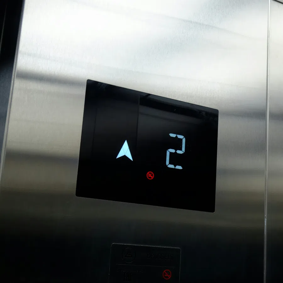 Digital elevator panel showing floor 2 and up arrow in a stainless steel elevator interior