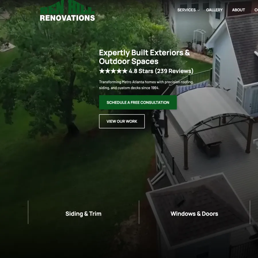 Aerial view of a renovated home exterior with deck, pergola, and green lawn surrounded by trees.