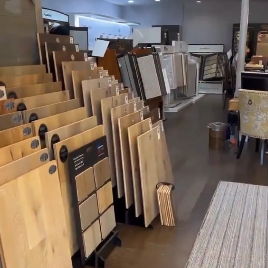 Interior of a flooring showroom with various wood and tile samples displayed on stands and racks under ceiling lights.