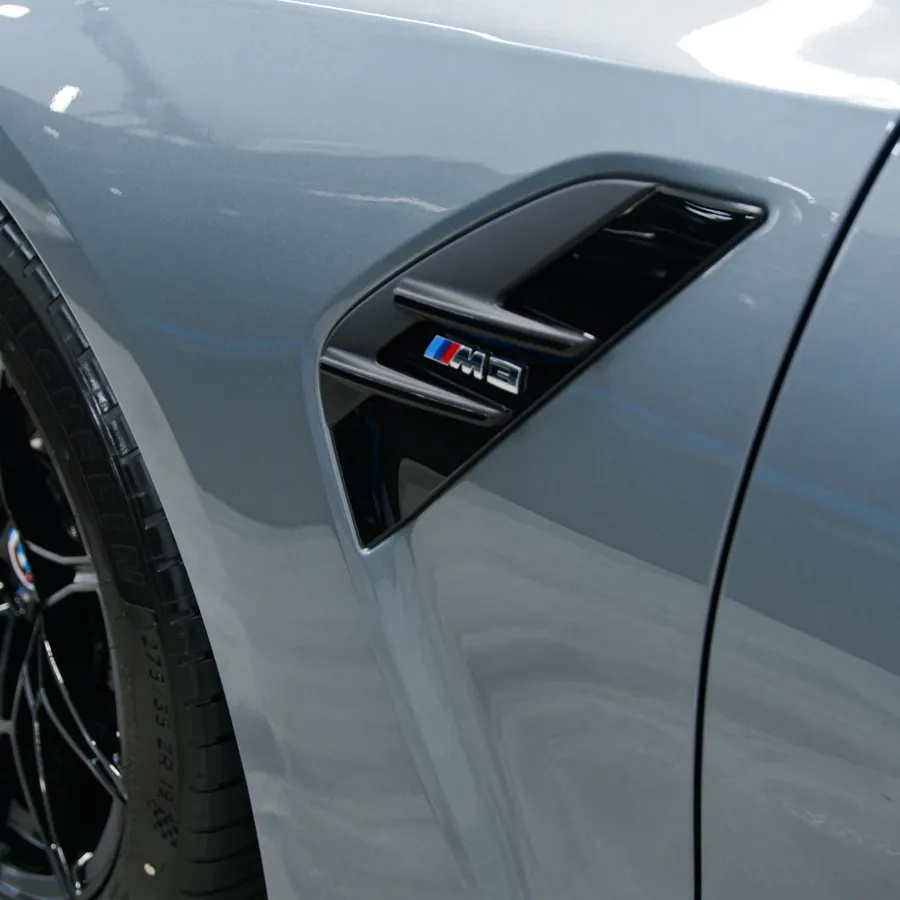 Close-up of a BMW M3 side vent and black alloy wheel on a metallic silver car body.
