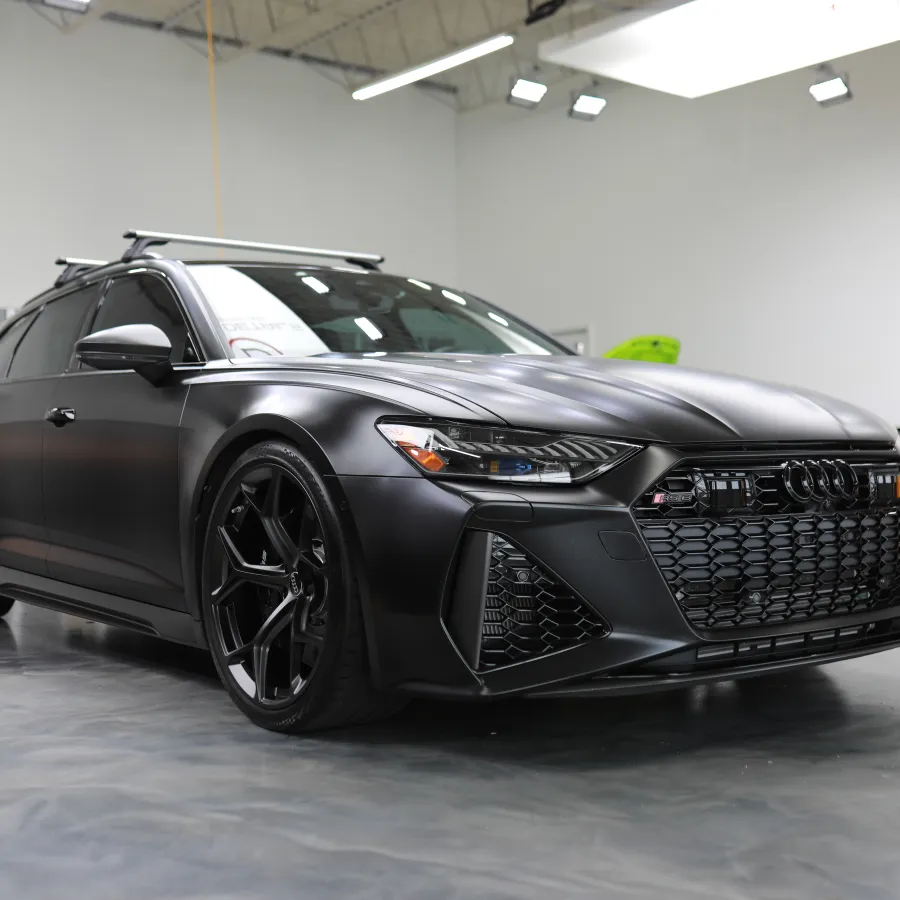 Matte black Audi sports car parked indoors with sleek design and black alloy wheels in showroom.