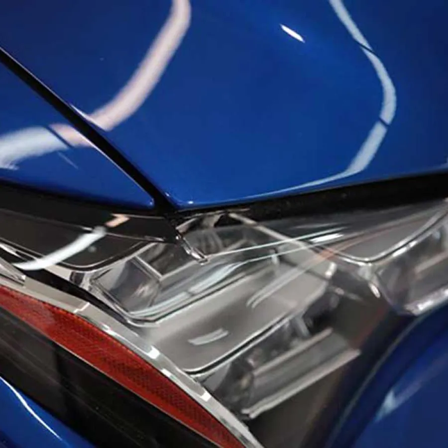 Close-up of a sleek blue car's modern headlight with reflective surface and sharp design lines