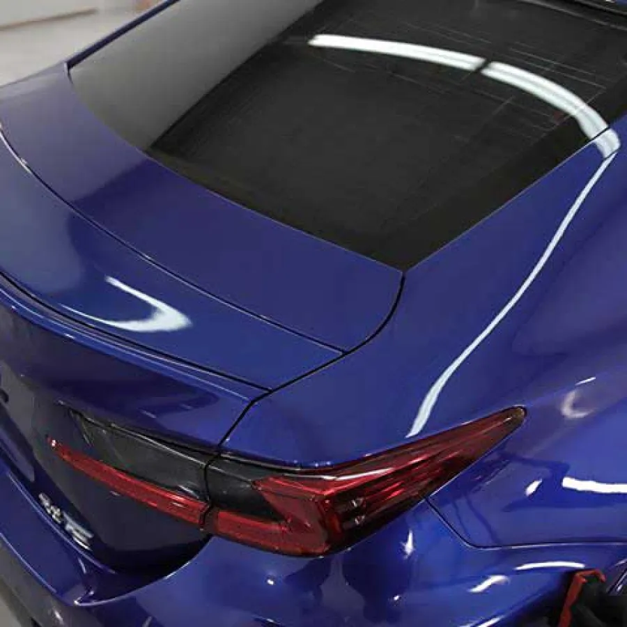 Close-up of rear section of shiny blue luxury sedan highlighting taillight and trunk details.