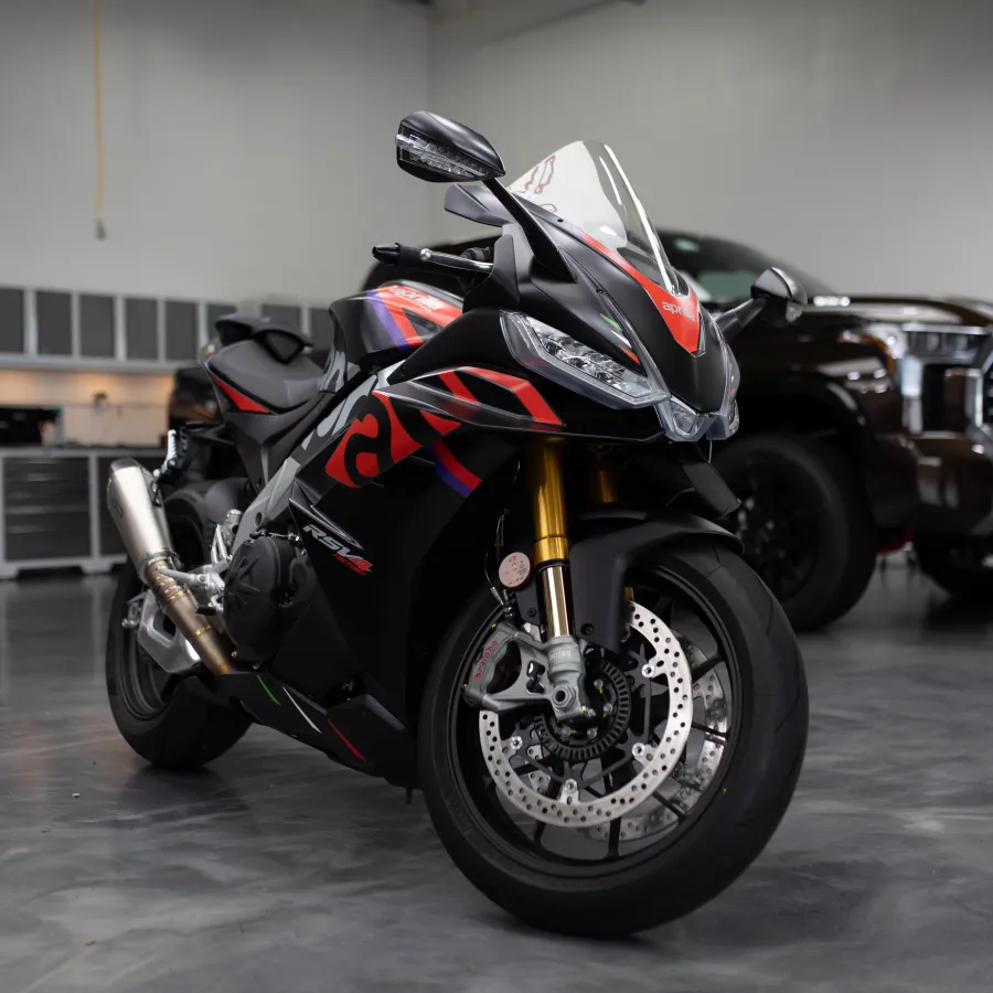 Black and red sport motorcycle parked indoors with a dark SUV and garage cabinets in the background.