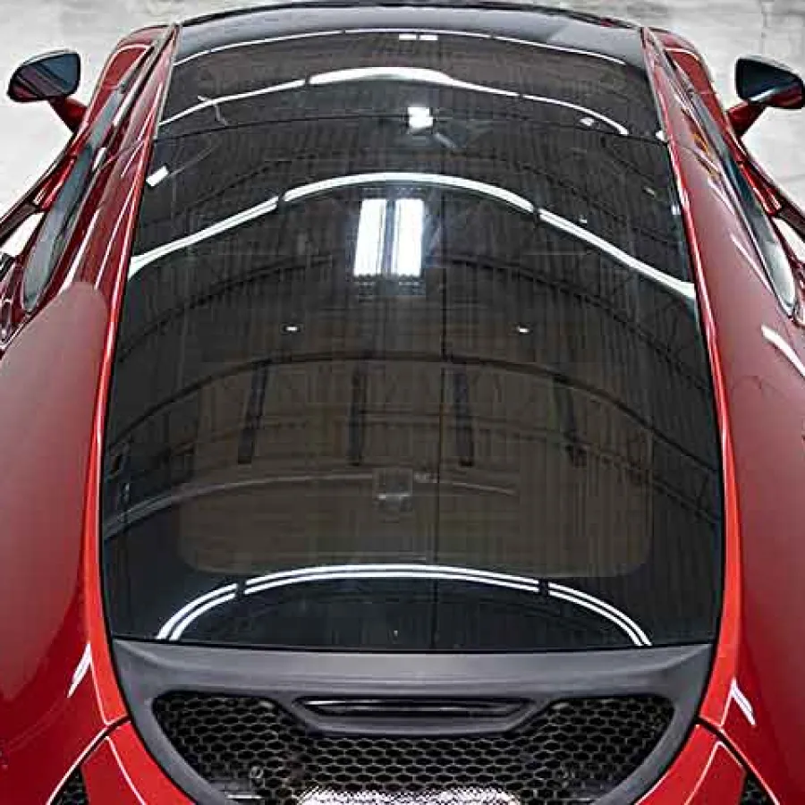 Top view of a shiny red sports car interior and rear window in a sleek modern showroom.