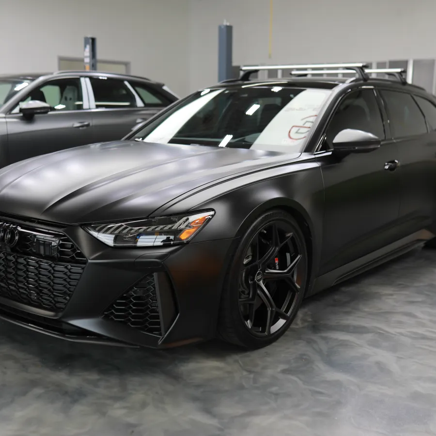 Matte black Audi RS6 Avant parked in a modern garage with sleek design and black alloy wheels.