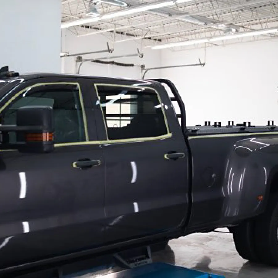 Black dually pickup truck inside a clean automotive detailing garage with 'Simple Details' signage on wall.