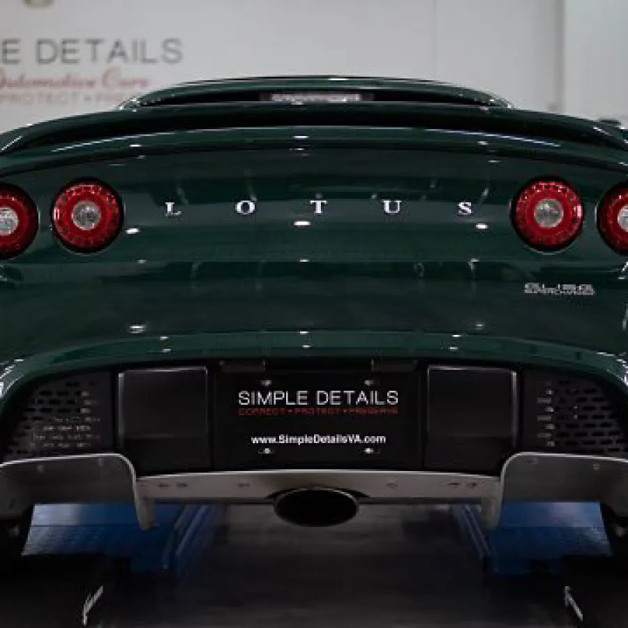 Rear view of a dark green Lotus sports car with round taillights and Simple Details license plate.