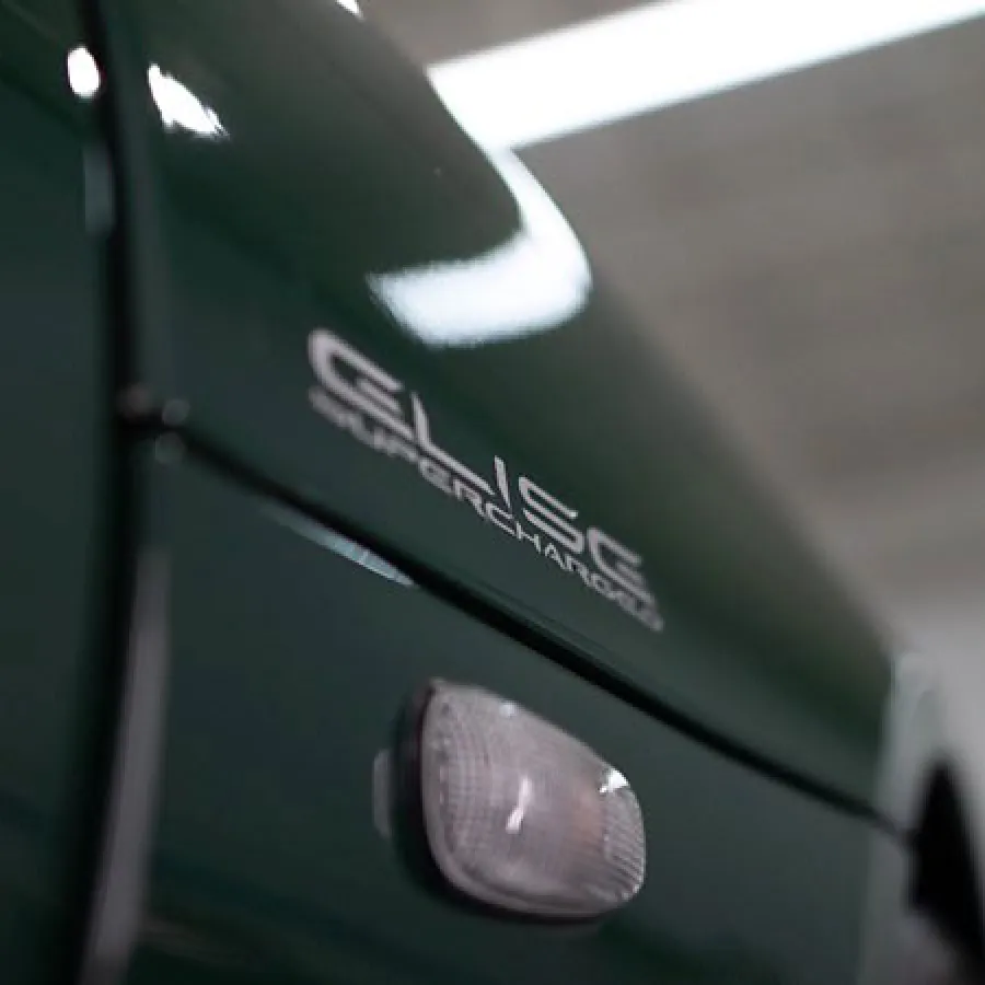 Close-up of a dark green car side panel featuring a CSL supercharger badge and side marker light.