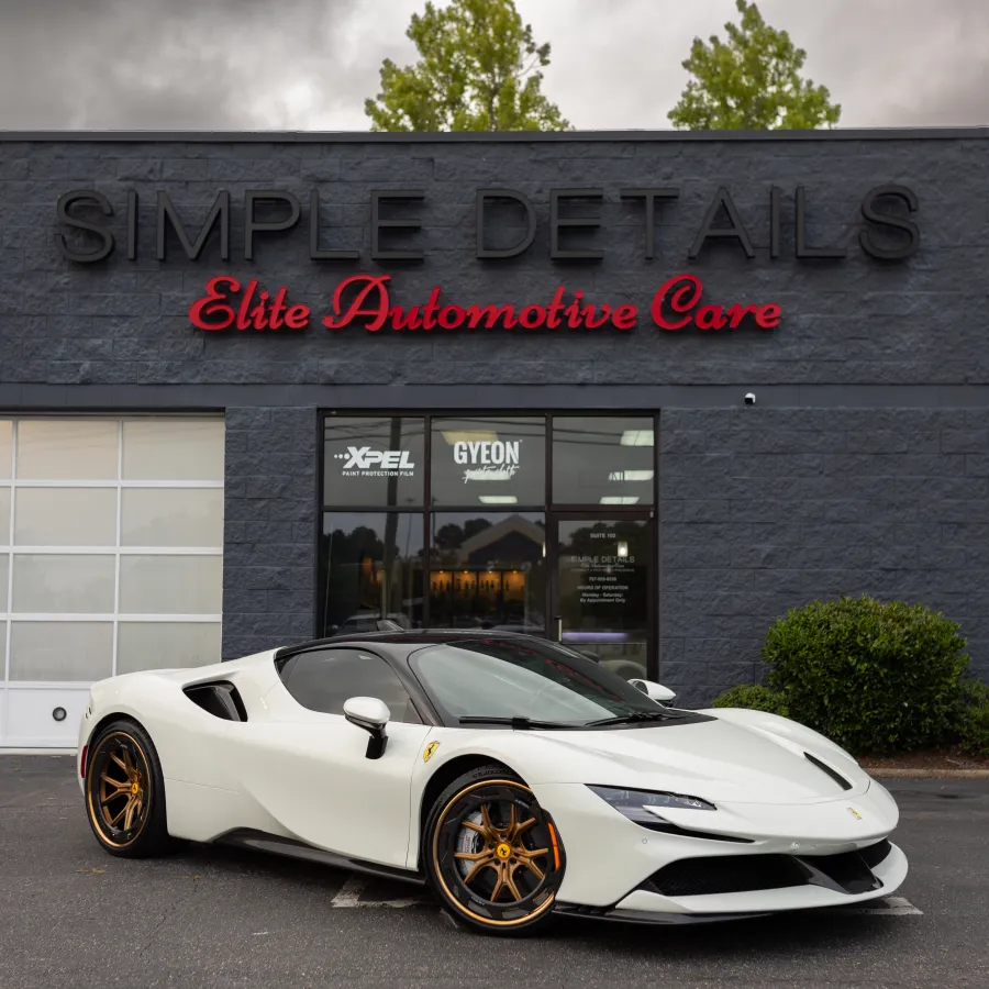White luxury sports car with gold rims parked in front of Simple Details Elite Automotive Care building.