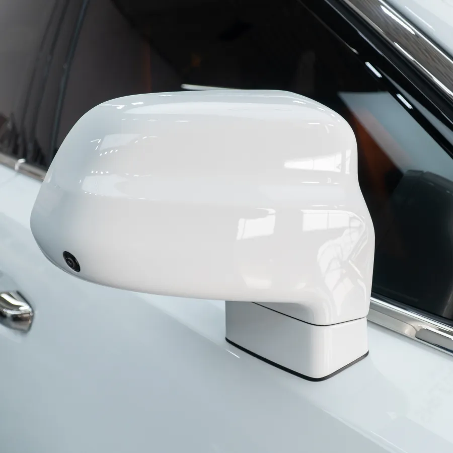 Close-up of a white car's side mirror with a sleek design and tinted window in a showroom setting