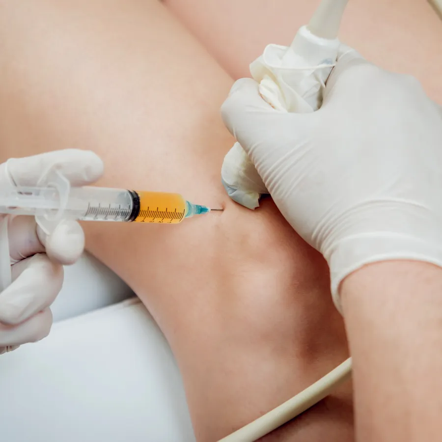 Medical professional using ultrasound guidance to inject medication into patient's knee joint.