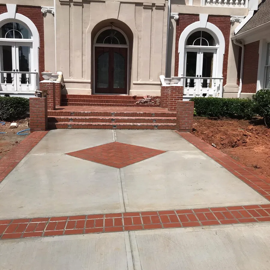 Front view of a house with a brick and concrete driveway featuring a diamond brick pattern in the center.