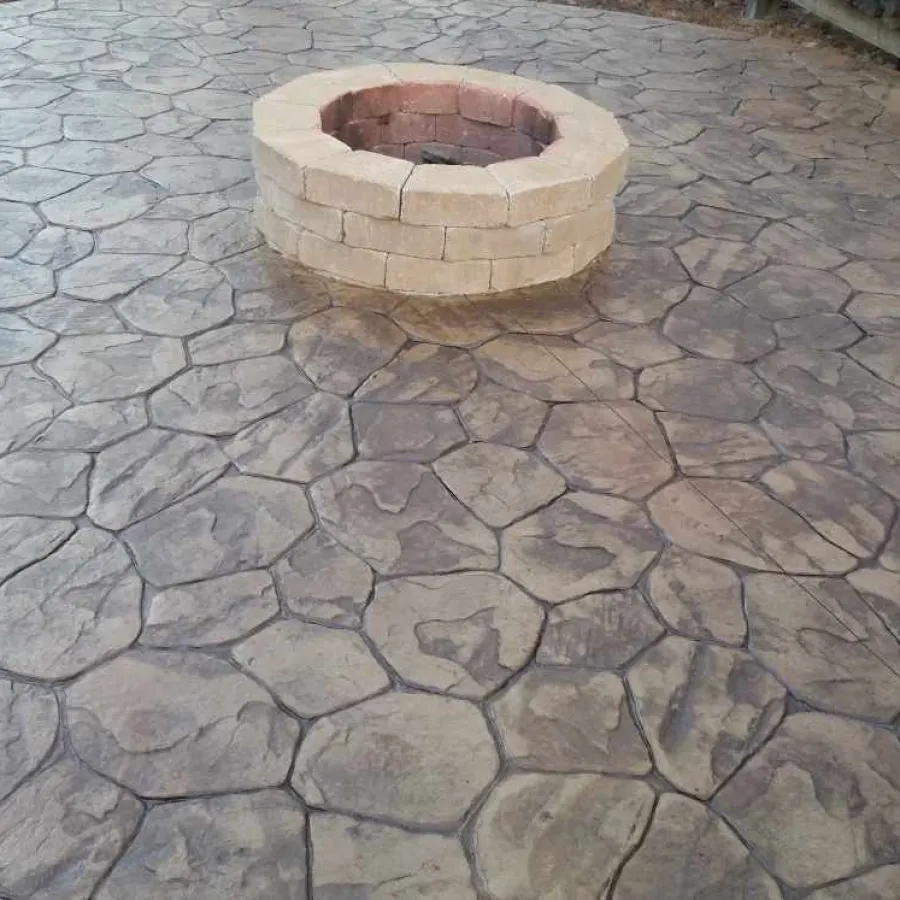 Round stone fire pit on decorative stamped concrete patio with irregular stone pattern and earth tones