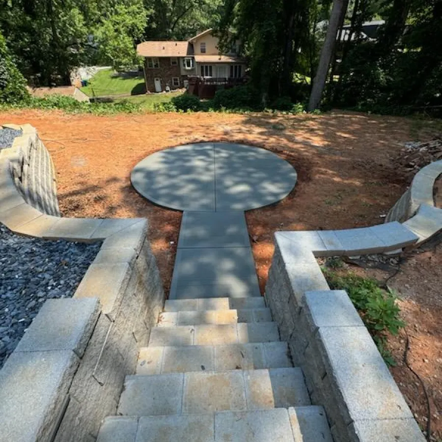 A view from above showing stone steps leading to a circular patio in a residential backyard.