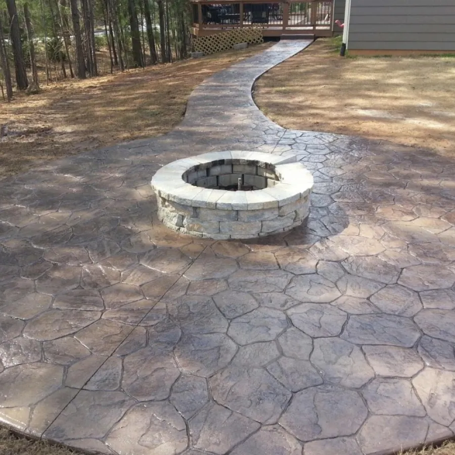 Beautifully designed stone patio with a circular fire pit surrounded by patterned concrete.