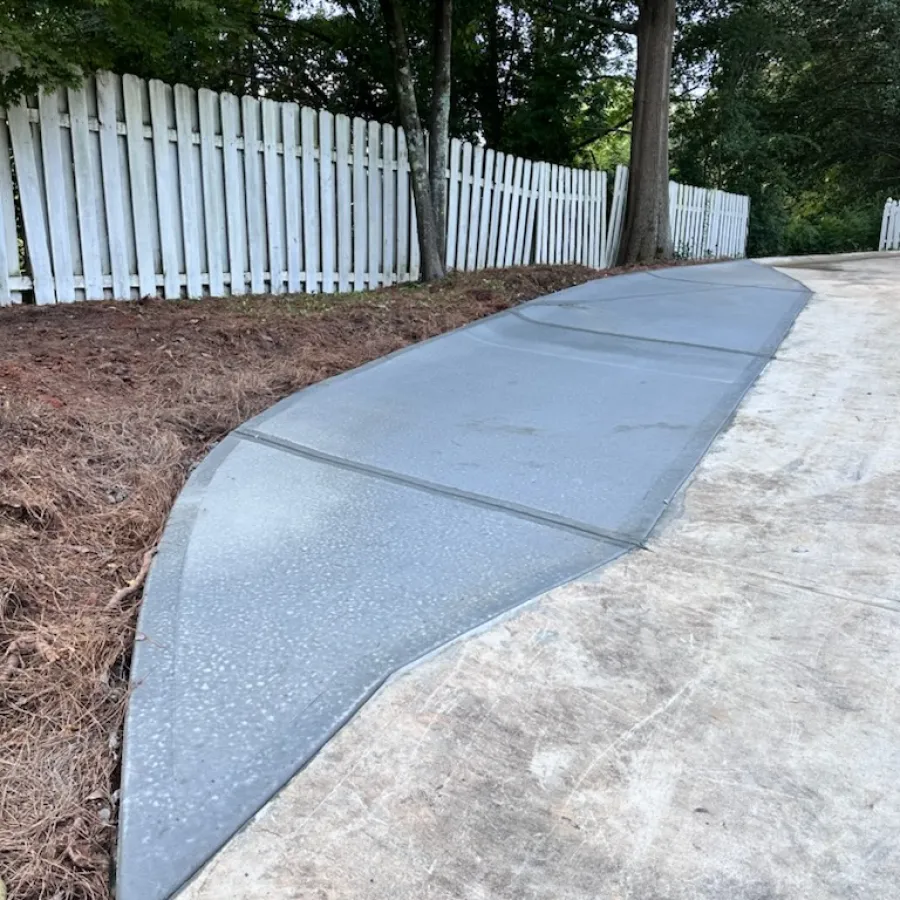 a concrete walkway with a white fence