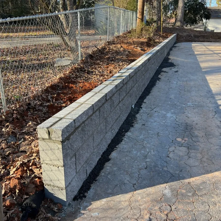 a concrete walkway with a fence and trees on the side