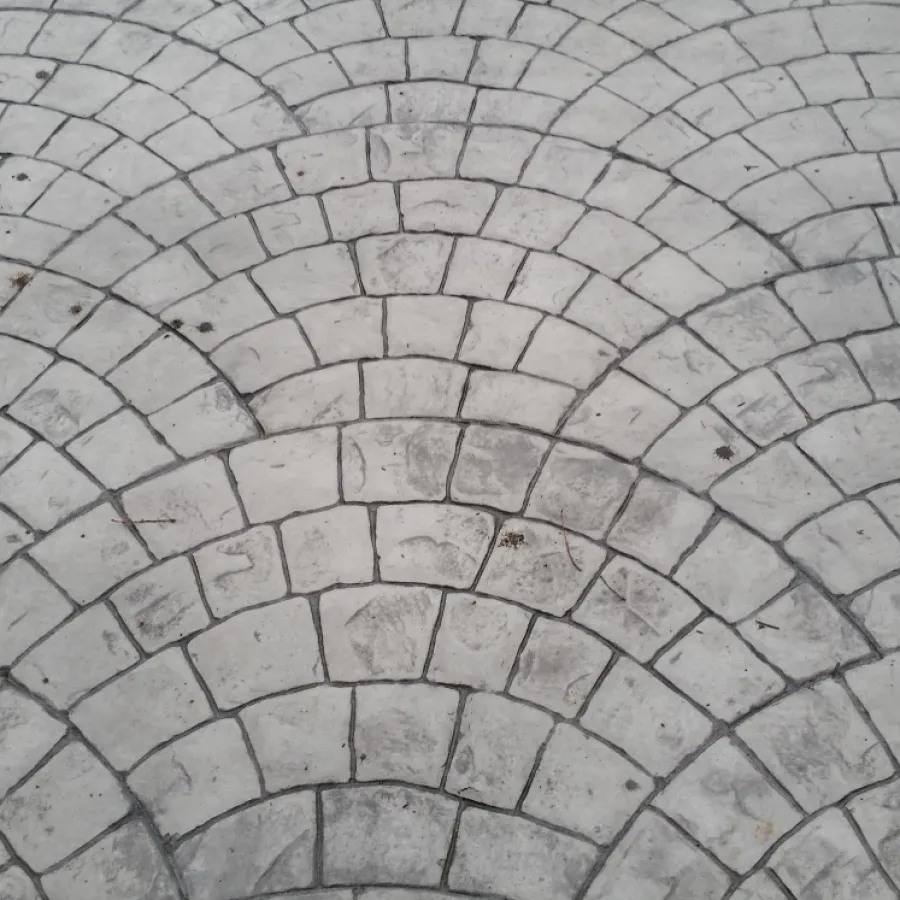 Close-up of grey stone pavement arranged in repeating semi-circular patterns with slight wear marks