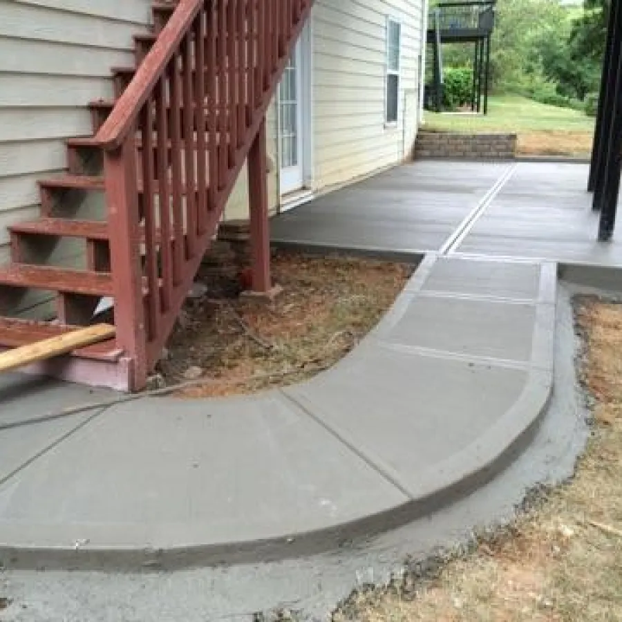 a driveway with a railing and a house in the background