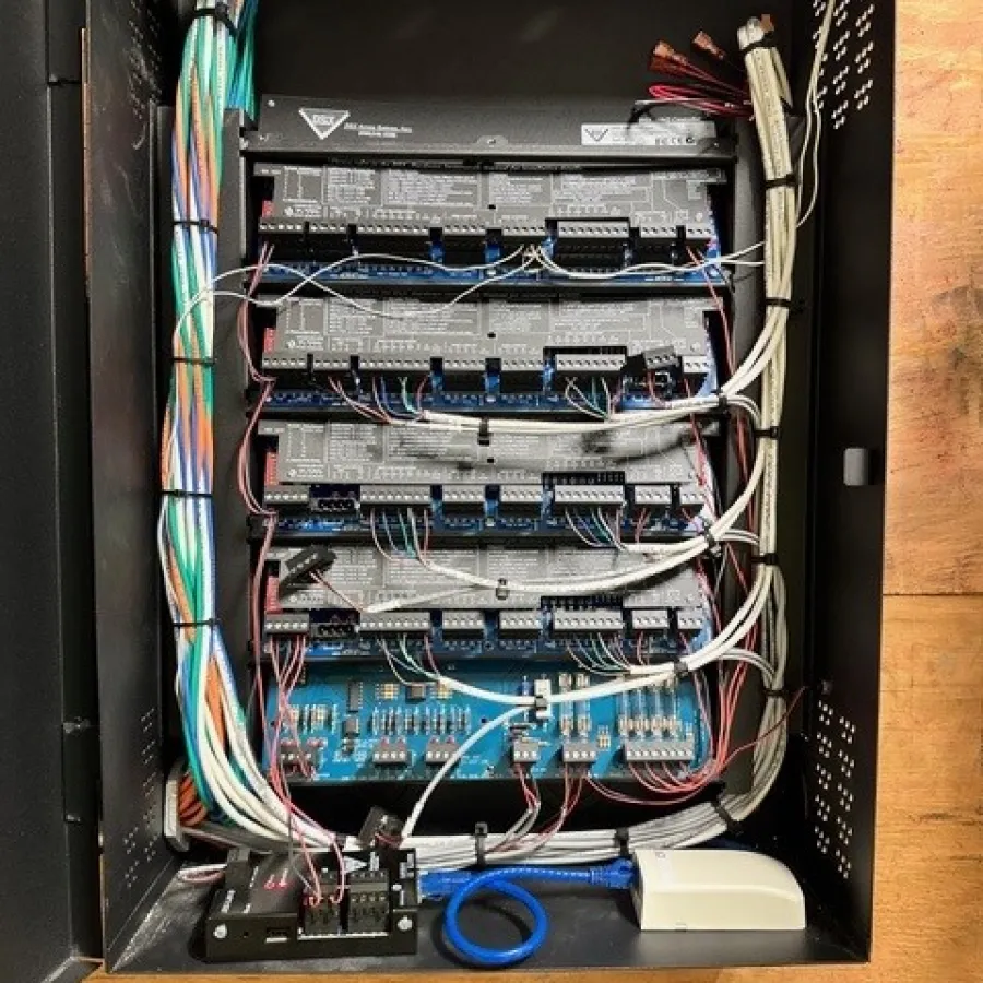Open electrical control panel with organized multicolor wiring and multiple circuit boards mounted inside a black metal enclosure