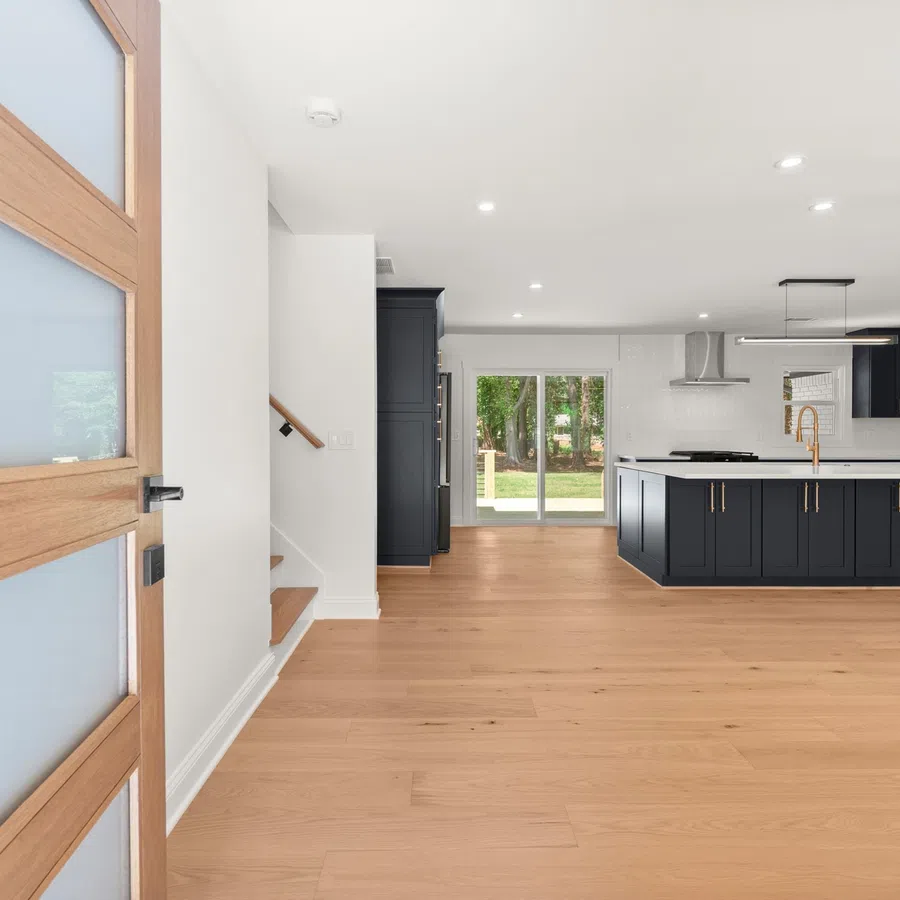 Open concept kitchen with navy blue island, light wood floors, white walls, and large glass sliding doors.
