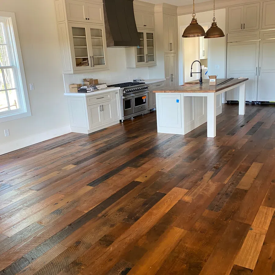 Spacious kitchen with white cabinetry, large island, dark wood flooring, and modern stainless steel appliances.