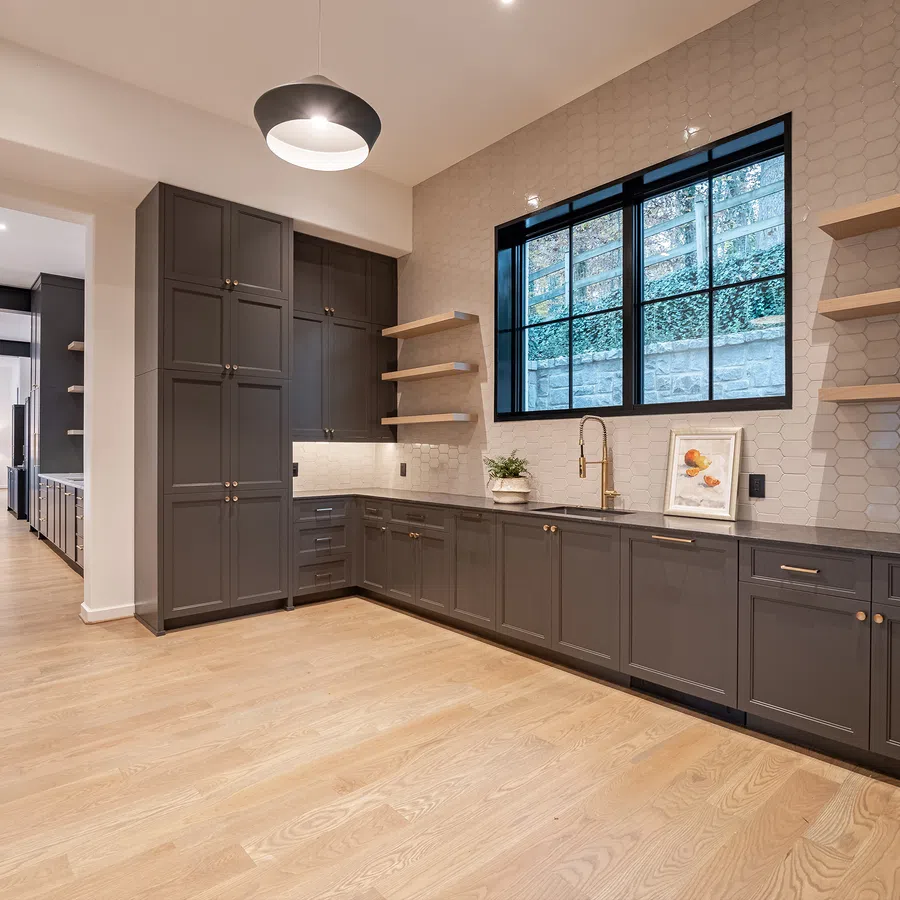 Modern kitchen with dark gray cabinetry, wood floors, hexagon tile wall, large window, and open shelving
