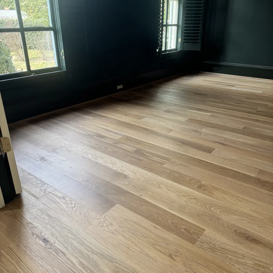 Spacious room with natural light, black walls, and newly installed light oak hardwood flooring.