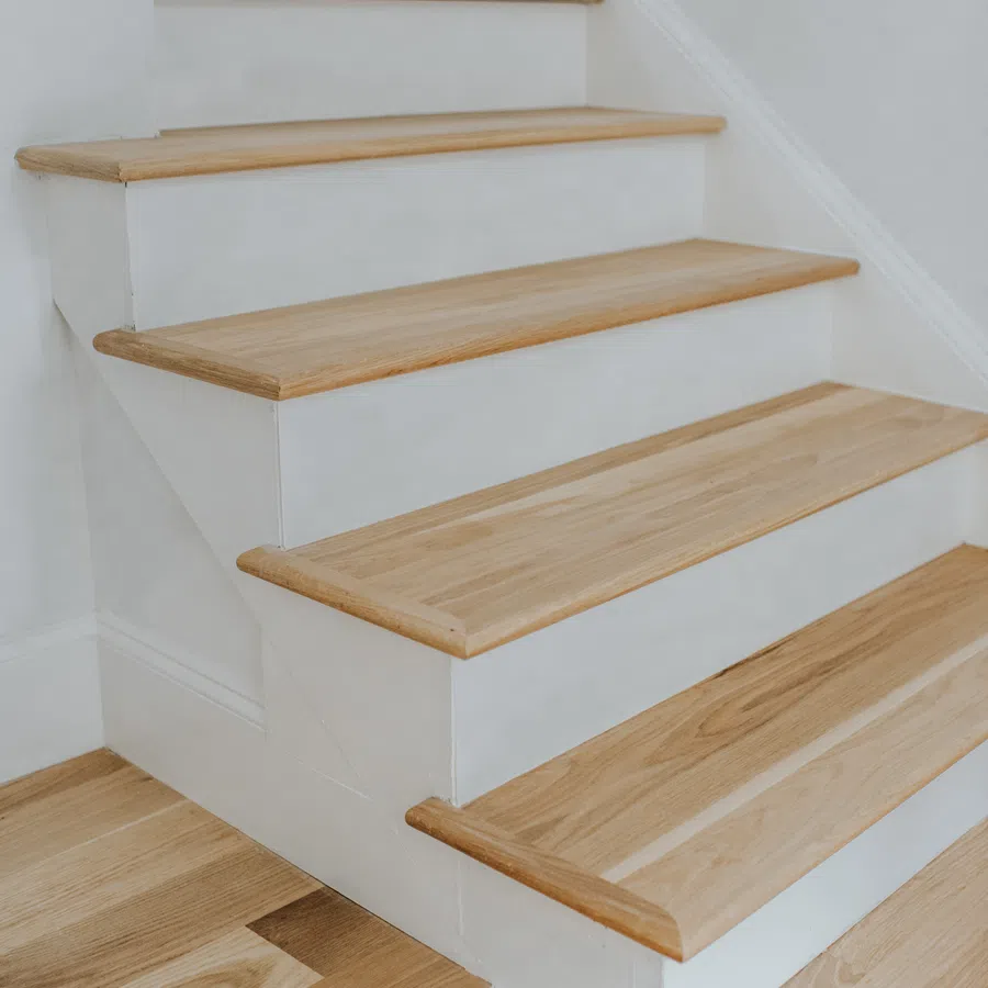 Close-up of wooden stairs with white risers and natural wood treads in a modern interior.