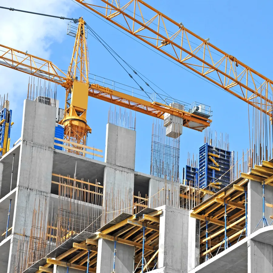 Construction site featuring a yellow crane and reinforced concrete structures under blue sky.