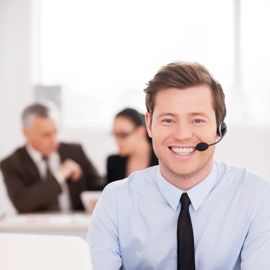 Smiling customer service representative with headset in a modern office setting.