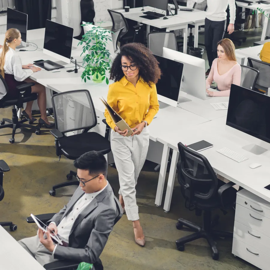 Modern office workspace with diverse employees collaborating and working at desks.