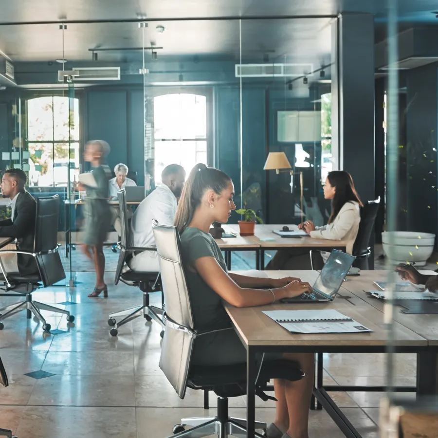 Modern office workspace with diverse professionals collaborating and working on laptops.