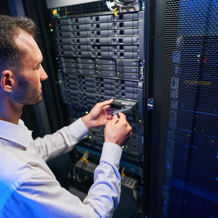 Technician installing a server component in a data center with blue lighting effect.