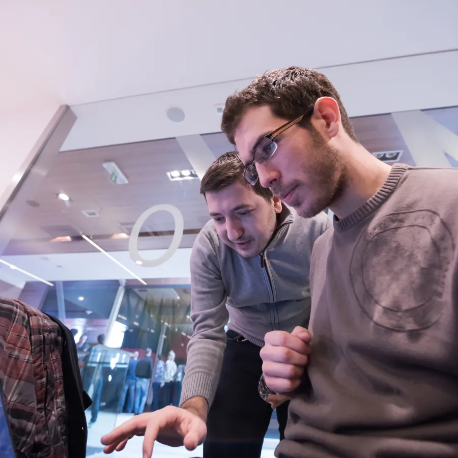 Two men collaborating over a laptop in a modern workspace environment.