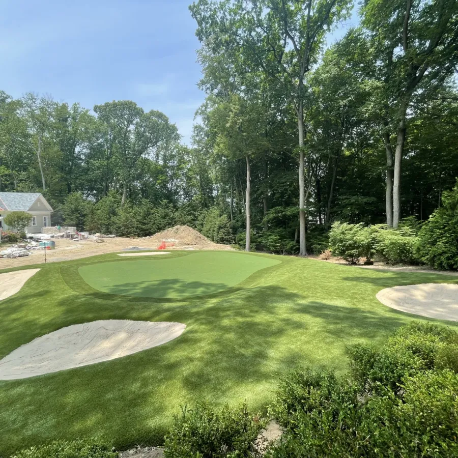 a golf course with trees and a house in the background