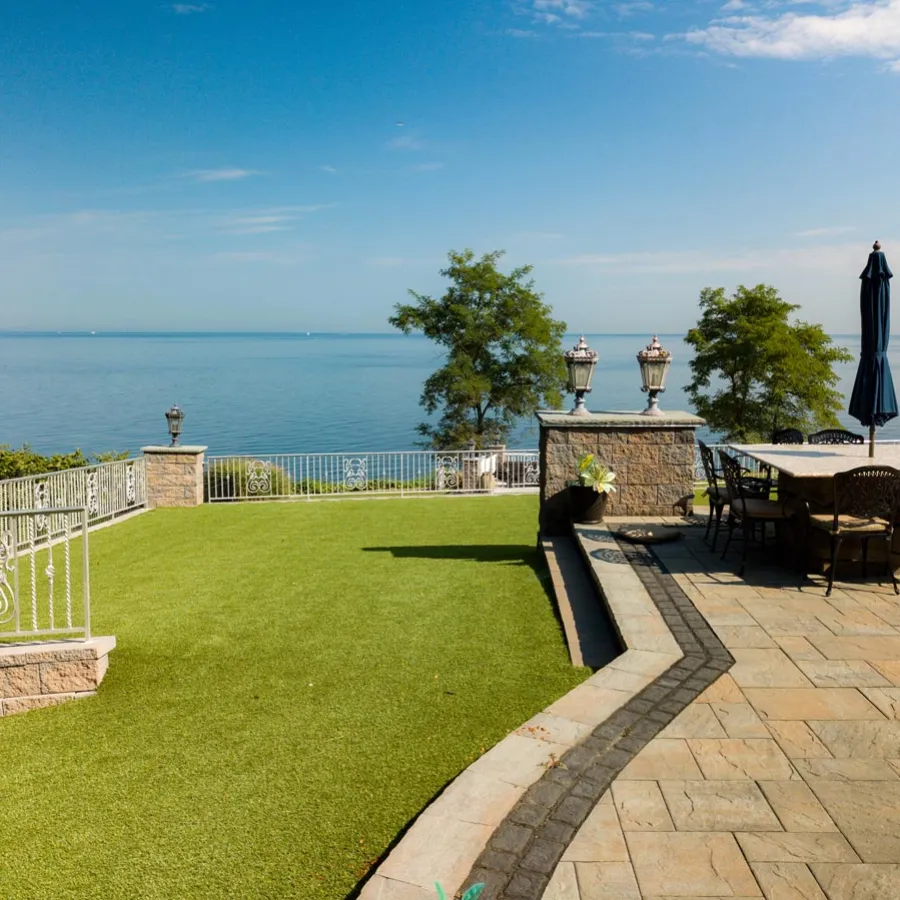 a patio with tables and chairs and umbrellas by a body of water