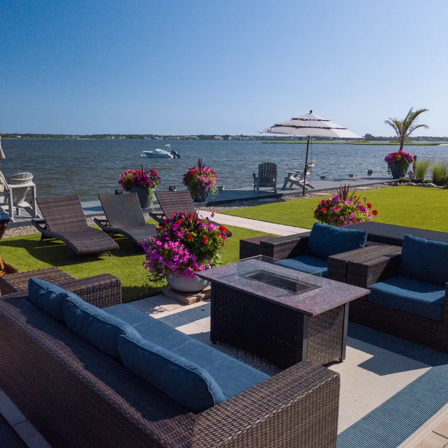 a patio with chairs and tables and umbrellas overlooking a body of water