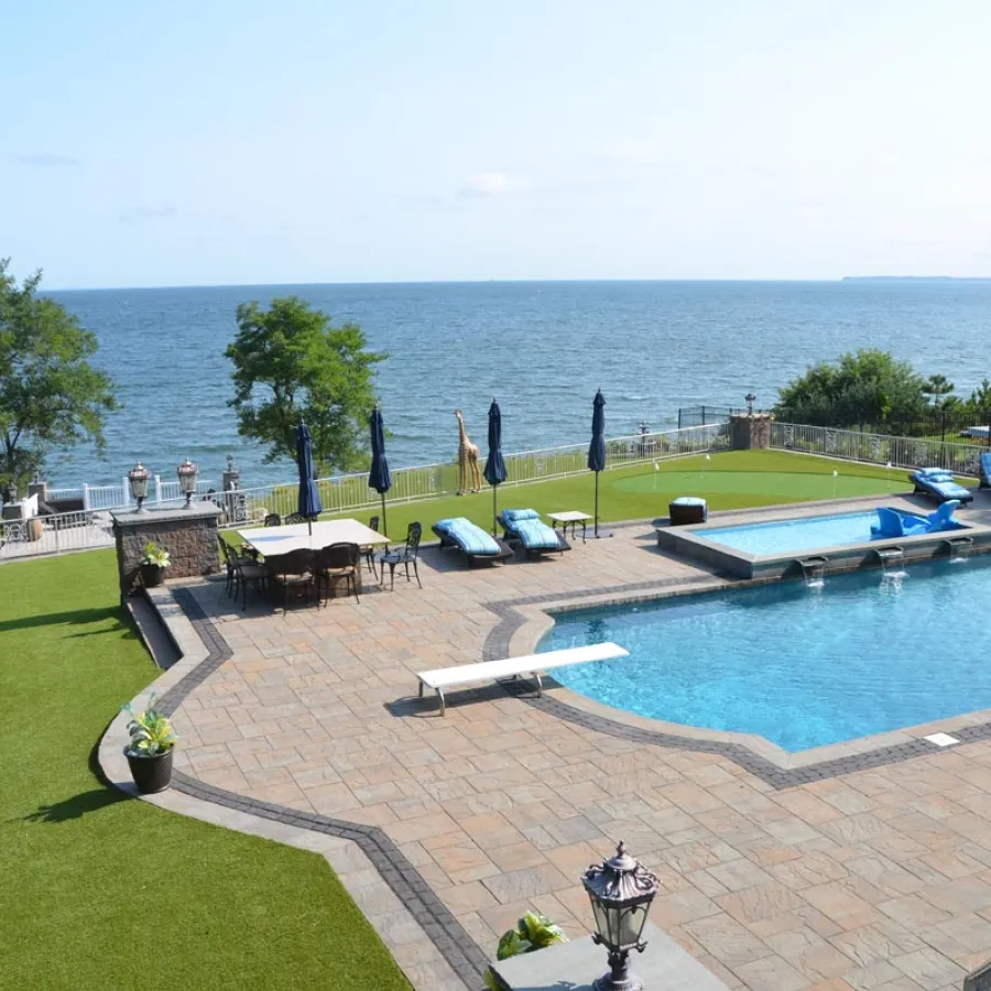 a pool with lounge chairs and umbrellas by a beach